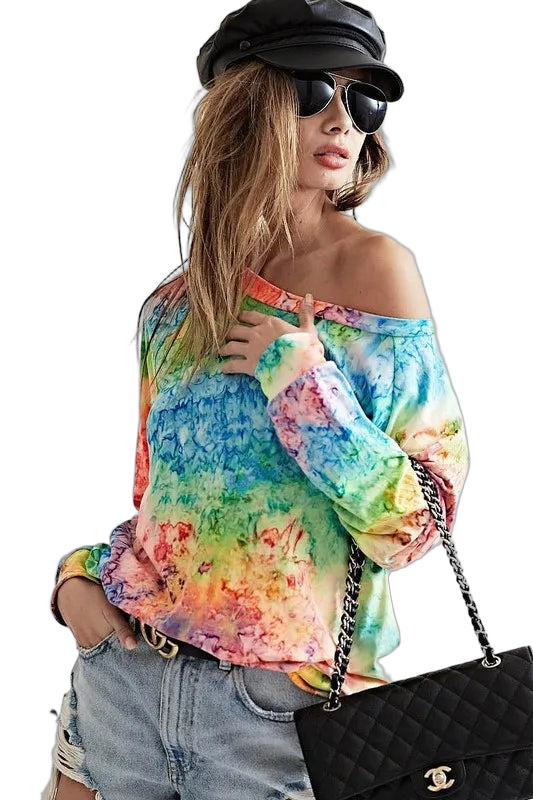 Model wearing multicolor tie-dye off-shoulder long-sleeve knit top with distressed denim shorts and quilted chain bag