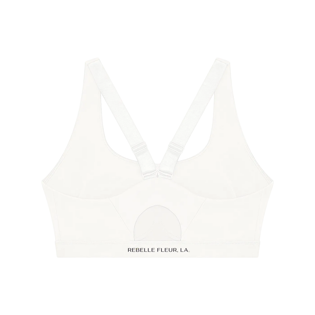 Back of white sports bra with V straps, adjustable hardware, stitched semi-circle detail and 'REBELLE FLEUR, LA.' on band.