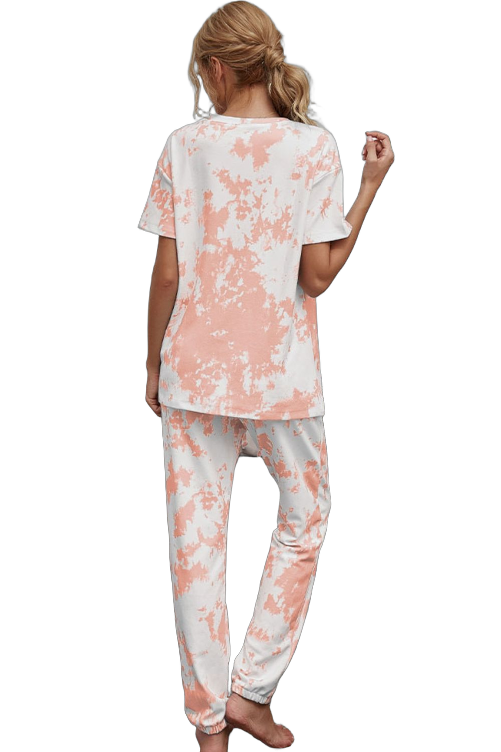 Back view of model wearing short-sleeve tie-dye tee and jogger pants with peach and white pattern, ponytail, barefoot