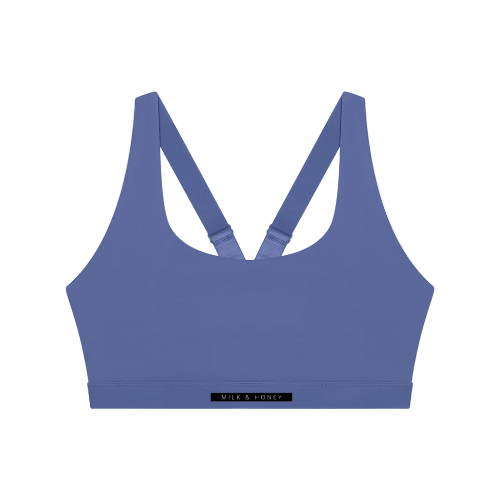 Scoop-neck sleeveless sports bra with adjustable crossed straps and narrow underband labeled 'MILK & HONEY'.