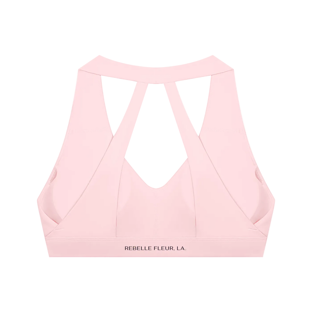 Light pink cropped sports bra with wide crisscross back straps and 'REBELLE FLEUR, LA.' printed on the band
