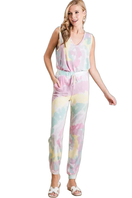 Woman wearing sleeveless pastel tie-dye top tucked into matching drawstring pants with side pockets and white sandals