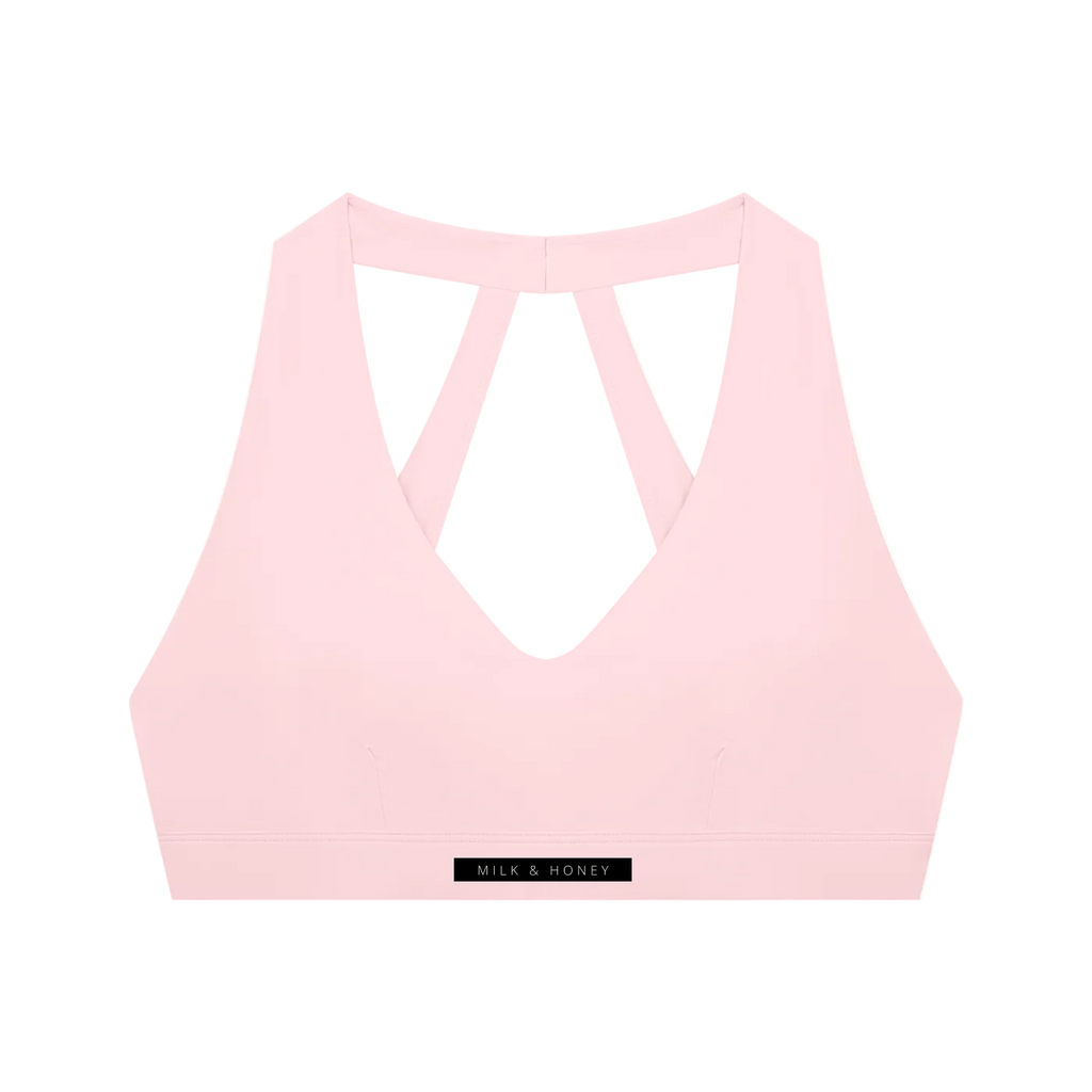Light pink cropped sports bra with deep V-front, double straps forming a triangular back and MILK & HONEY hem label
