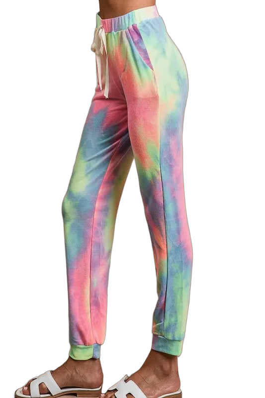 Model wearing pastel tie-dye jogger pants with drawstring waist, side pockets and cuffed ankles, paired with white sandals