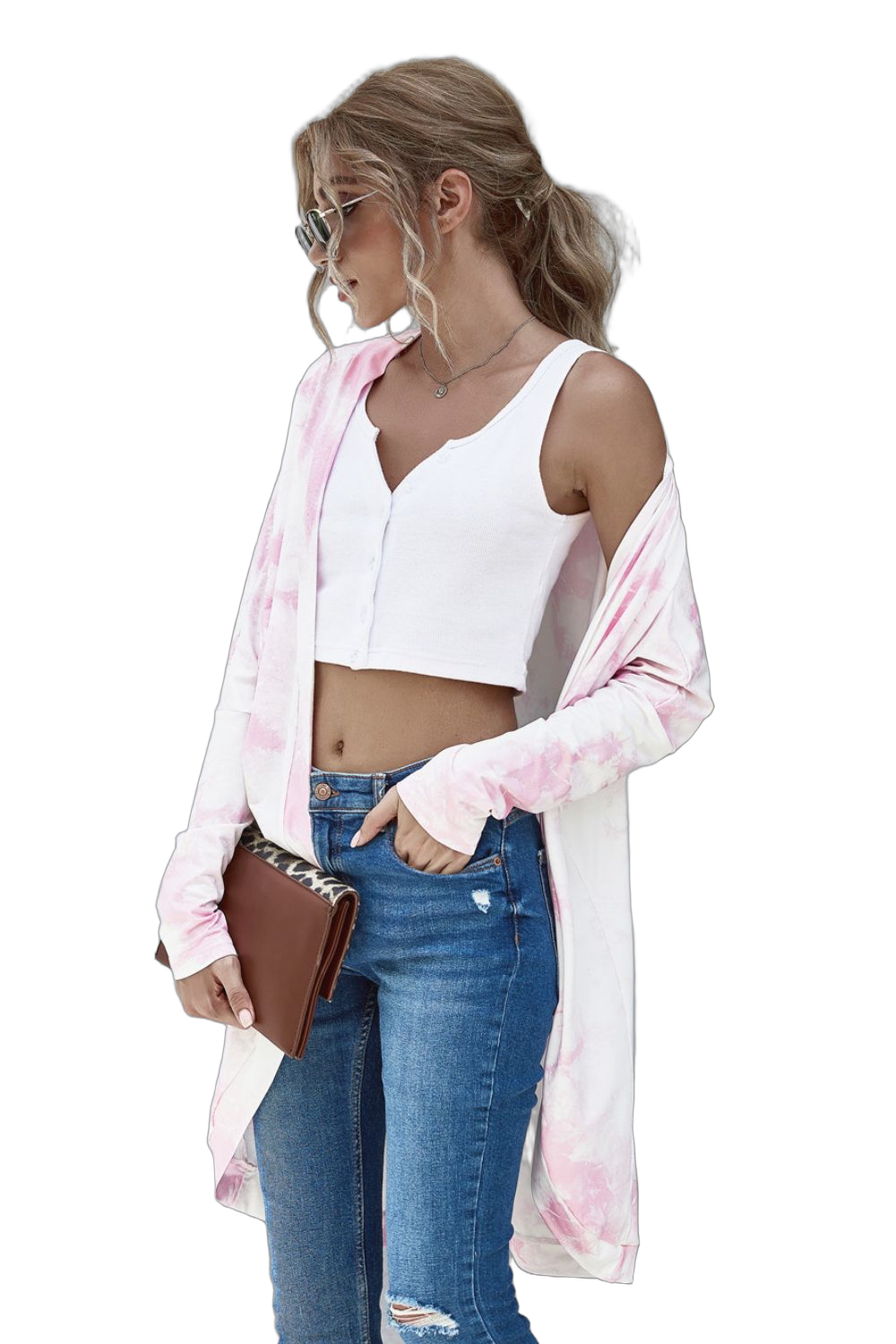 Woman wearing pink-and-white tie-dye open-front cardigan over white cropped tank, blue jeans, holding brown clutch.