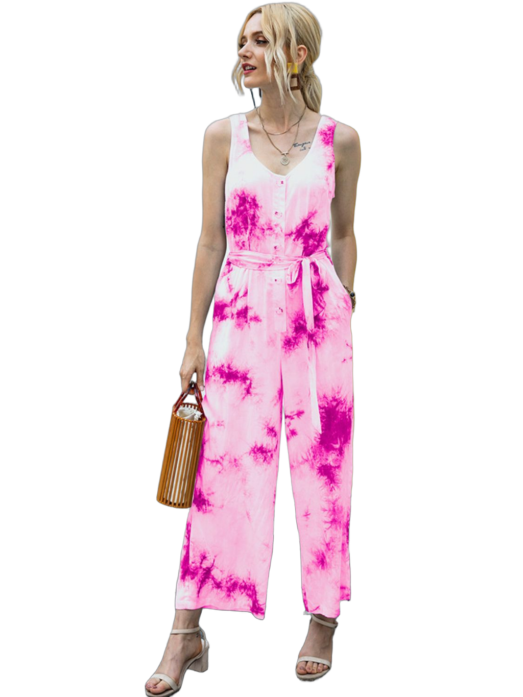 woman wearing sleeveless pink tie-dye wide-leg jumpsuit with tied waist and button front, holding a wooden handbag