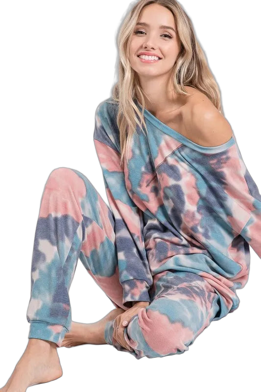 Smiling woman seated in pastel tie-dye jogger pants with cuffed ankles and matching off-shoulder top
