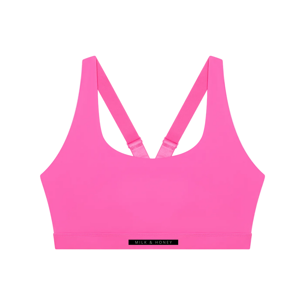 Bright pink sports bra with V-back adjustable straps and elastic underband labeled 'MILK & HONEY'