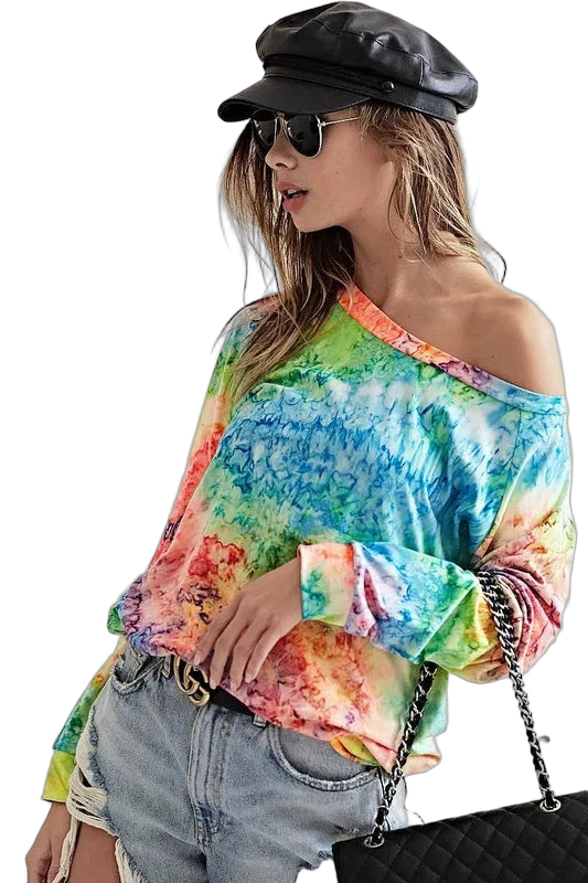 Woman in off-shoulder rainbow tie-dye long-sleeve tee, ripped denim shorts, black baker hat, sunglasses, quilted chain bag