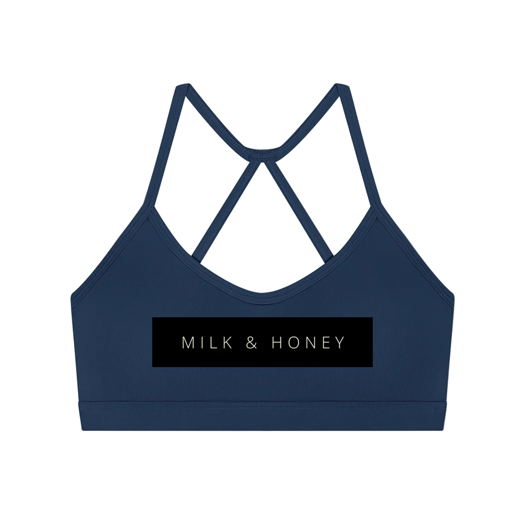 Navy sports bra with thin crisscross back straps and black rectangular 'MILK & HONEY' logo panel