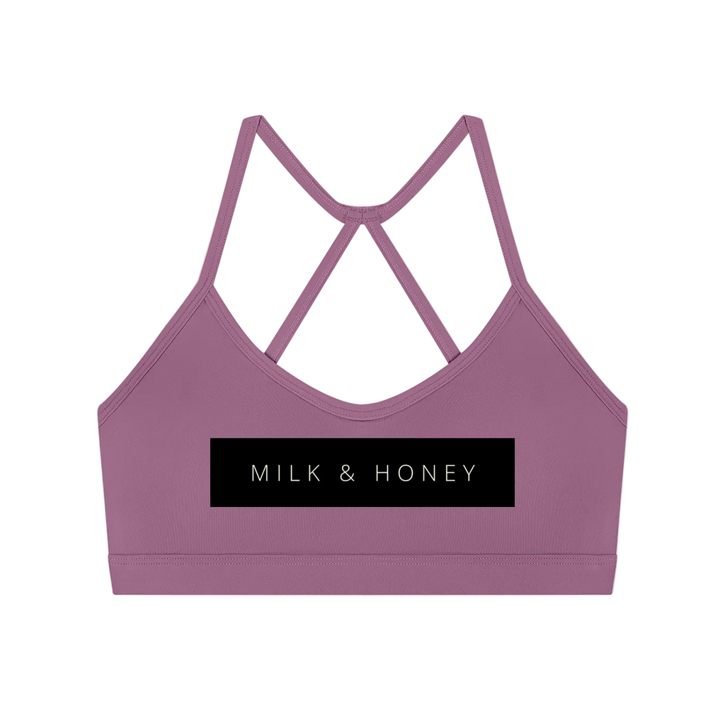 Mauve cropped sports bra with thin crisscross back straps and centered black 'MILK & HONEY' logo panel