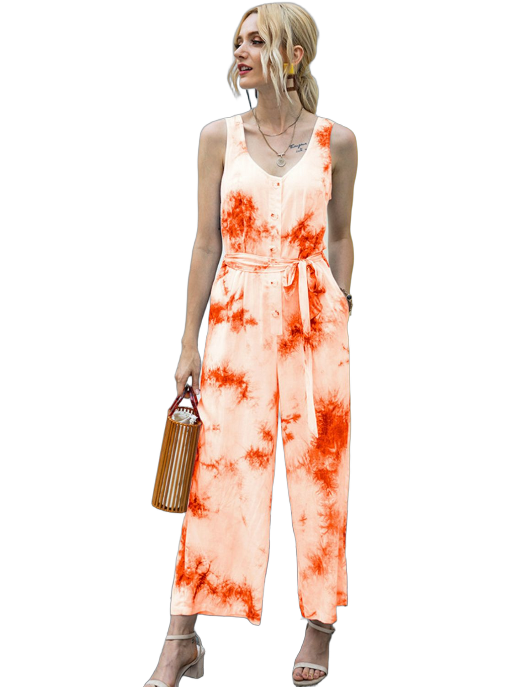 Sleeveless orange tie-dye jumpsuit with round neck, front buttons and self-tie waist; holding wooden handbag
