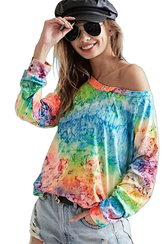Smiling woman in sunglasses and cap wearing off-shoulder rainbow tie-dye knit tee and distressed denim