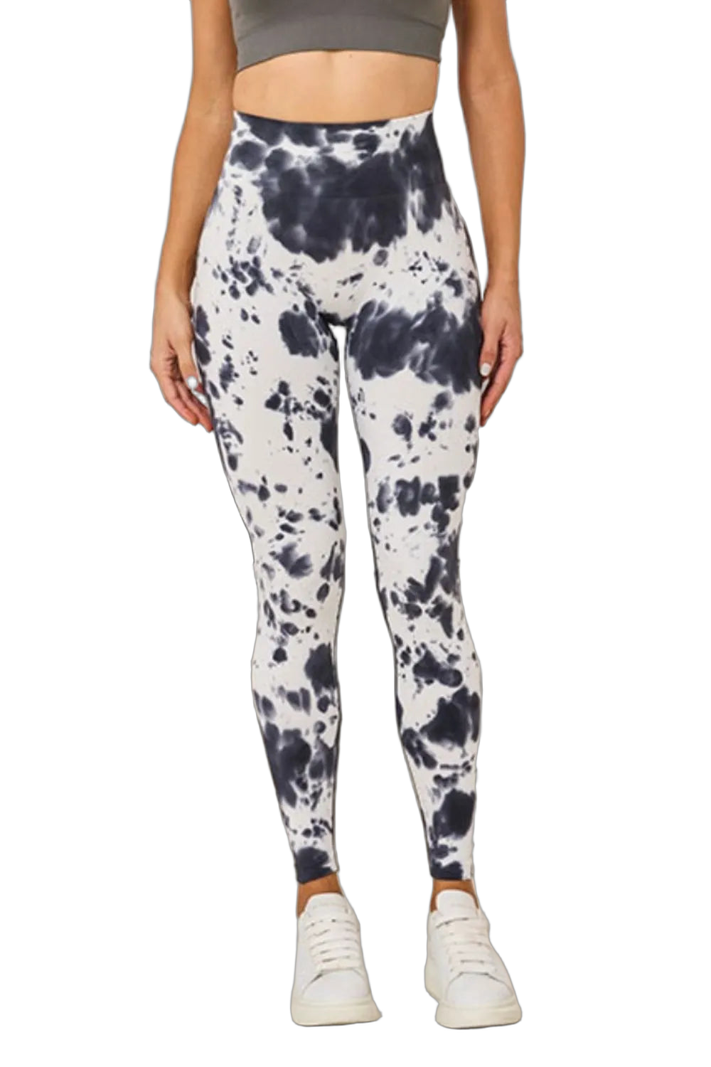 High-waist black and white tie-dye leggings on a model wearing a cropped gray top and white sneakers, black background