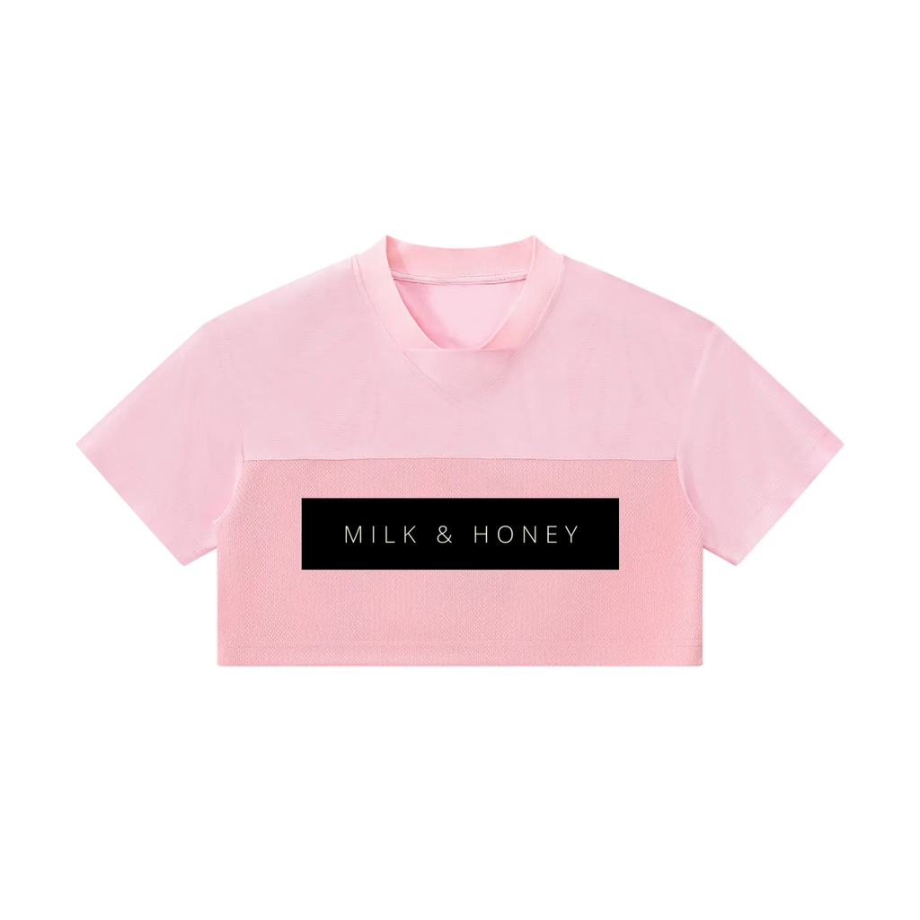 Pink cropped V-neck short-sleeve top with two-panel texture and black rectangular 'MILK & HONEY' logo