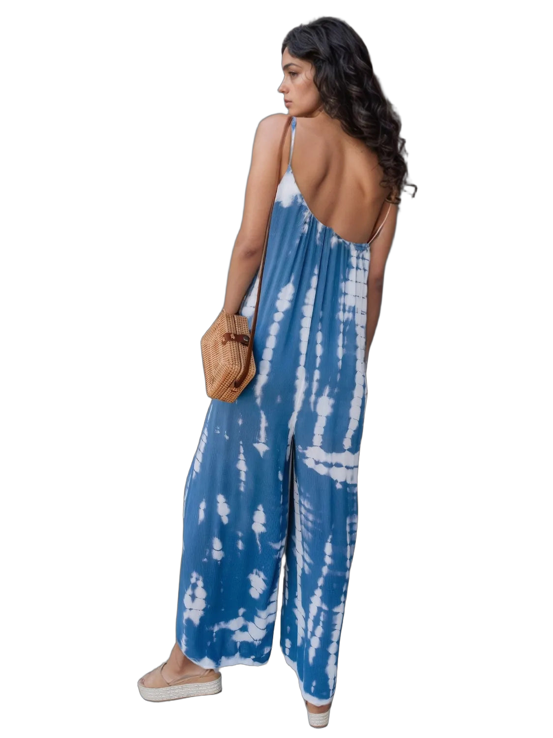 Woman in sky blue tie-dye V-neck spaghetti-strap jumpsuit with low open back, woven crossbody bag and espadrille platform…
