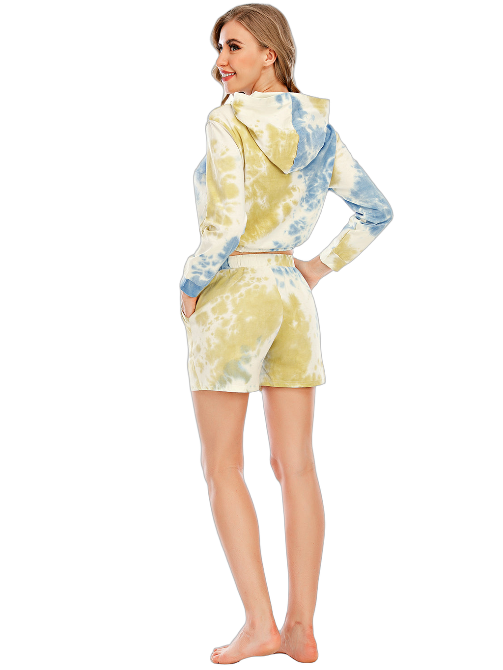 Woman seen from back wearing tie-dye hooded long-sleeve top and matching shorts, hands in pockets, barefoot