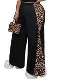 Black wide-leg pants with leopard-print side panels, elastic waistband; matching leopard-print handbag and white shoes.
