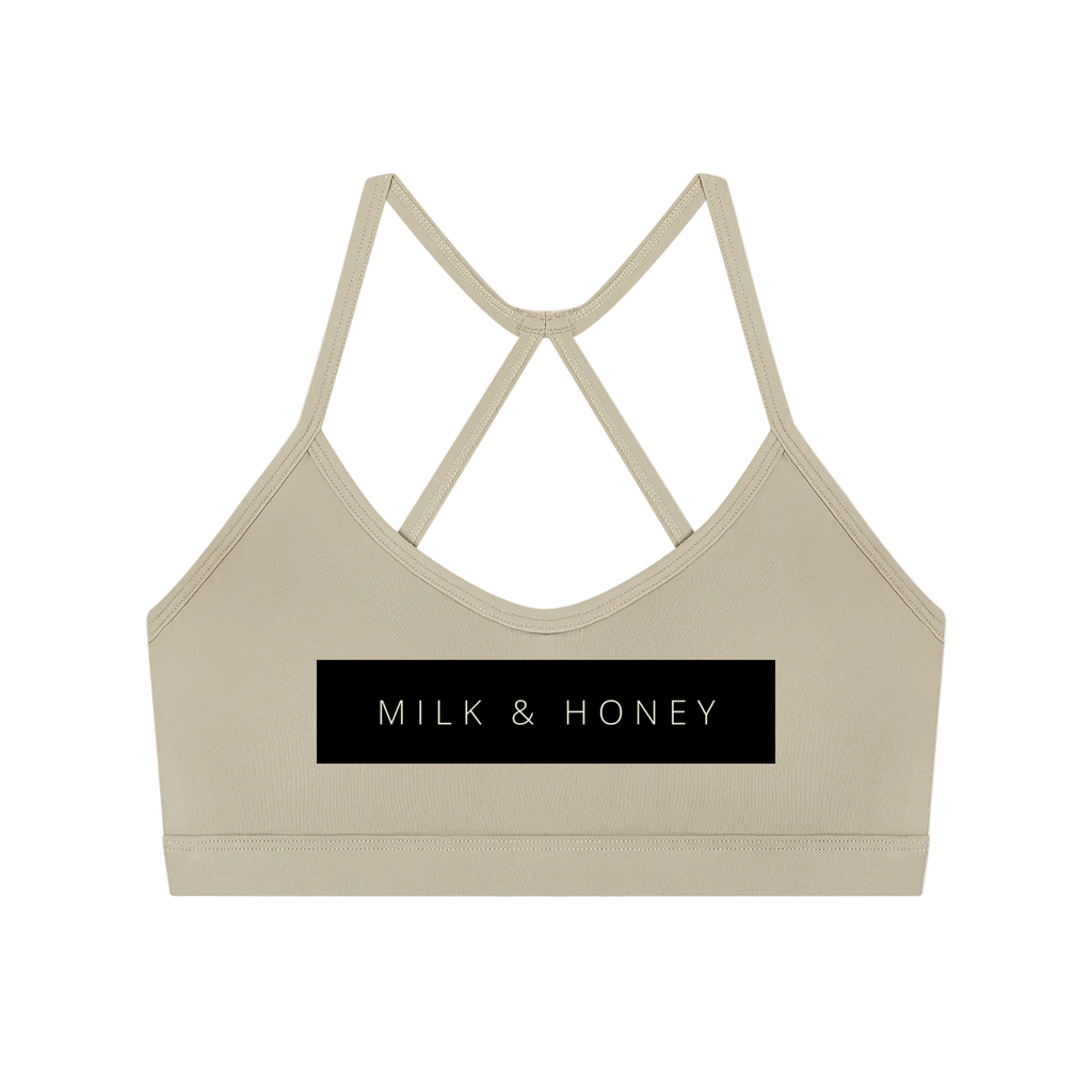 Cropped sleeveless sports bra with thin crisscross back straps and rectangular 'MILK & HONEY' print on front