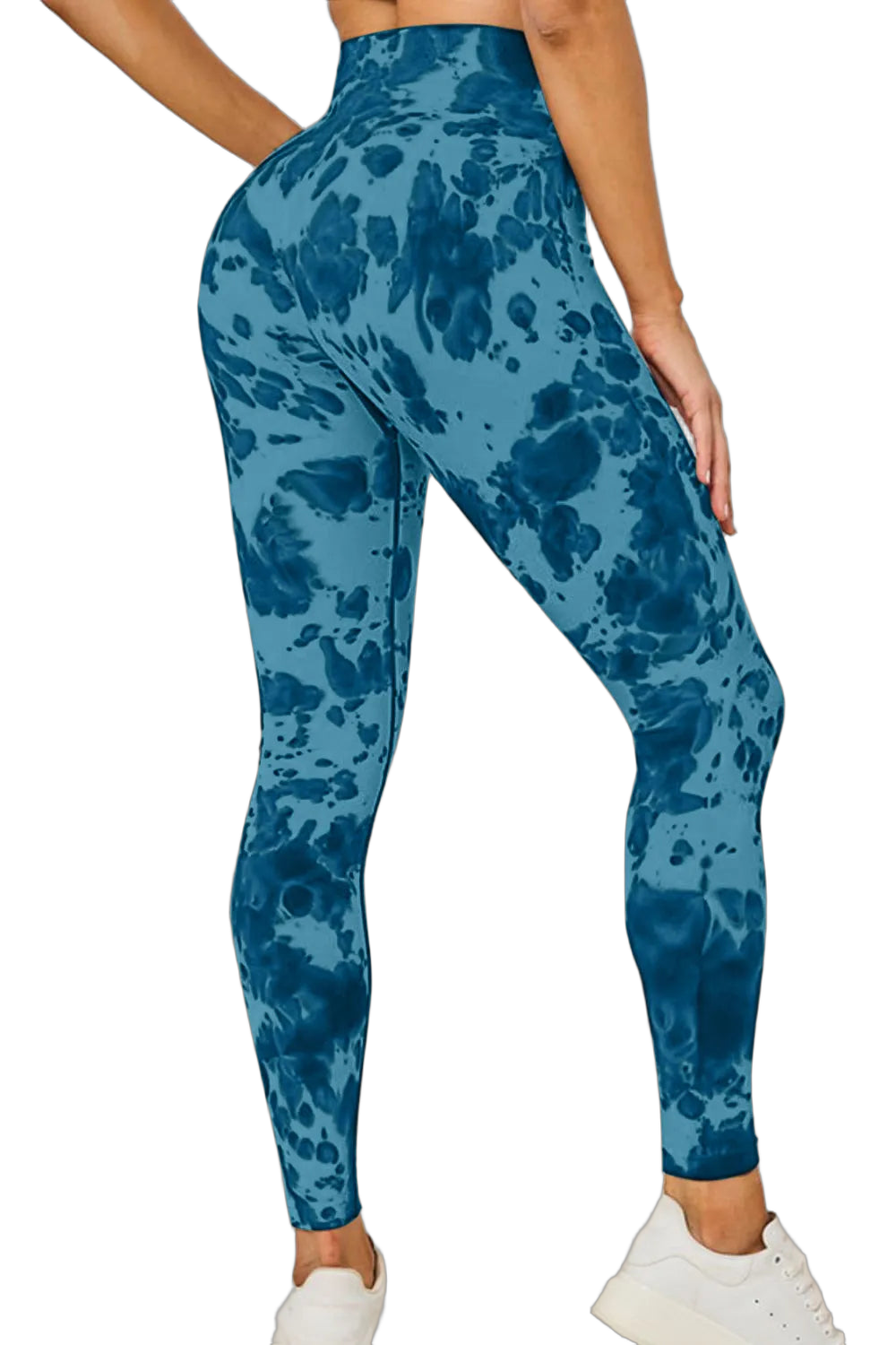 Blue tie-dye high-waist leggings on a standing model with hand on hip, white sneakers, black background