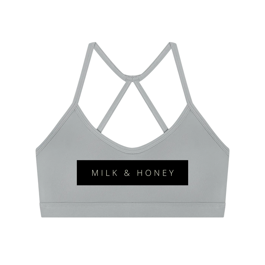 Gray crop sports bra with thin crisscross back straps and black MILK & HONEY rectangular logo panel