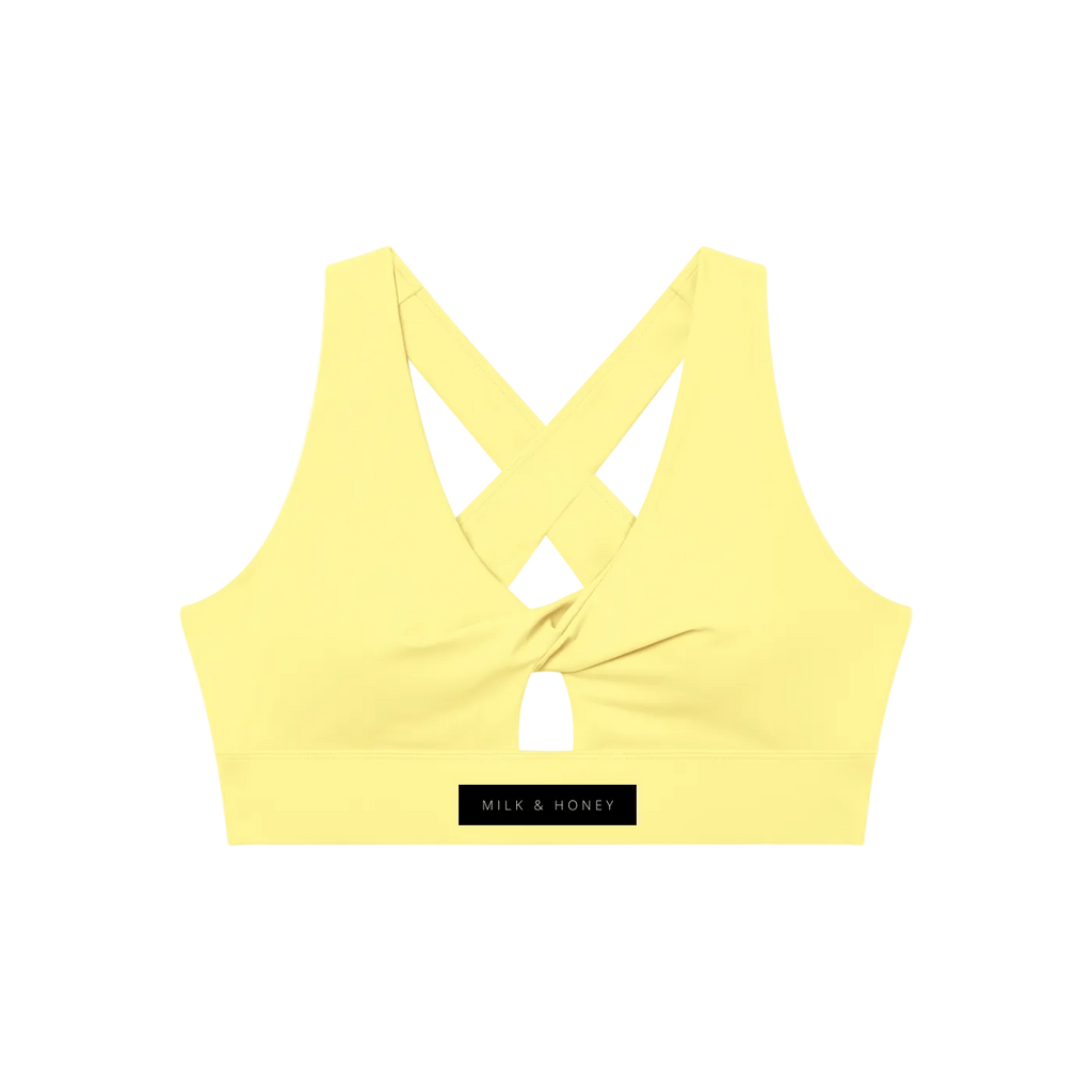 Pale yellow V-neck sports bra with twist front, small keyhole and crossed back straps; 'MILK & HONEY' logo on the band