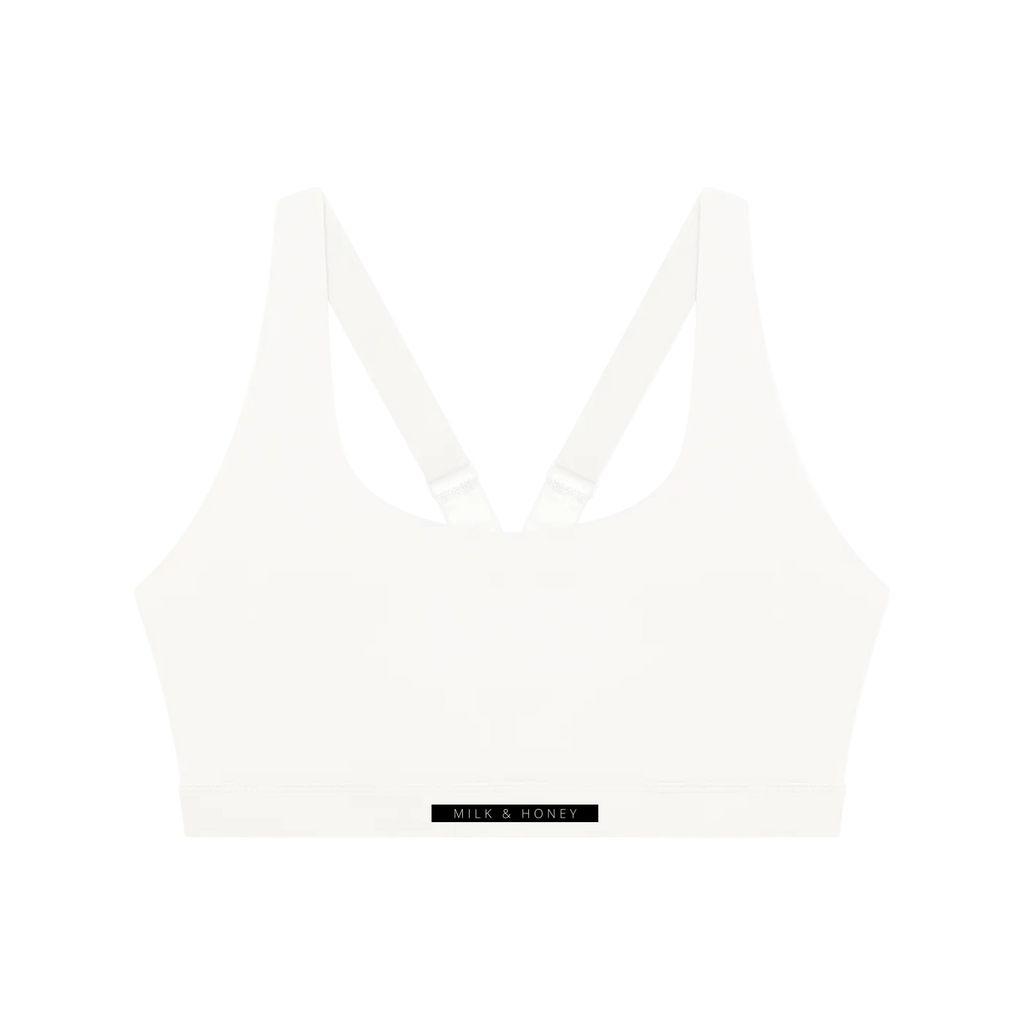 White crop sports bra with V-shaped racerback straps and wide elastic band labeled 'MILK & HONEY'