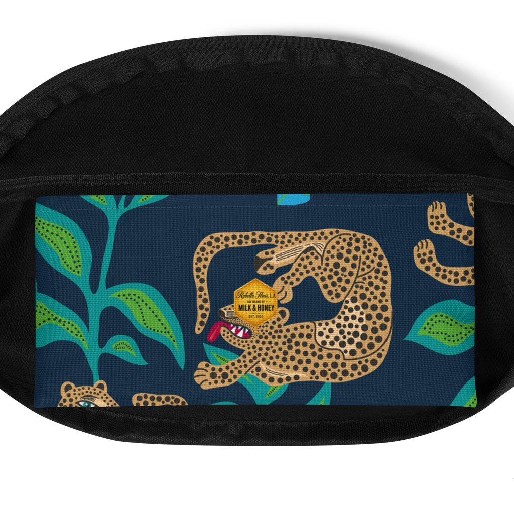 Front panel of waist bag with spotted leopard illustration, teal leaves on navy background and black zippered trim
