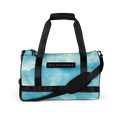 Black padded top handles and adjustable shoulder strap over a light blue watercolor duffel front with MILK&HONEY label