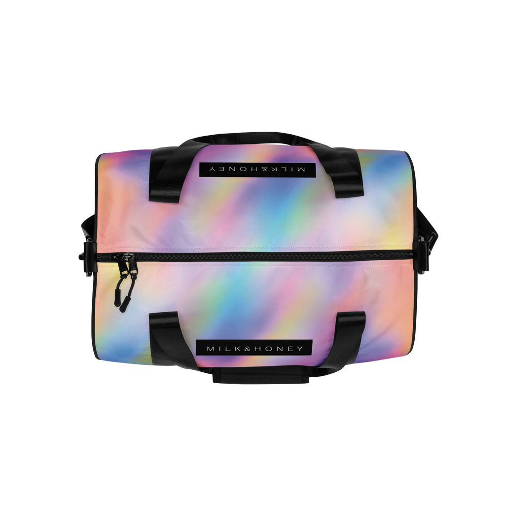 Top of duffel bag with pastel gradient print, black padded handles, MILK & HONEY label and front zipper pocket