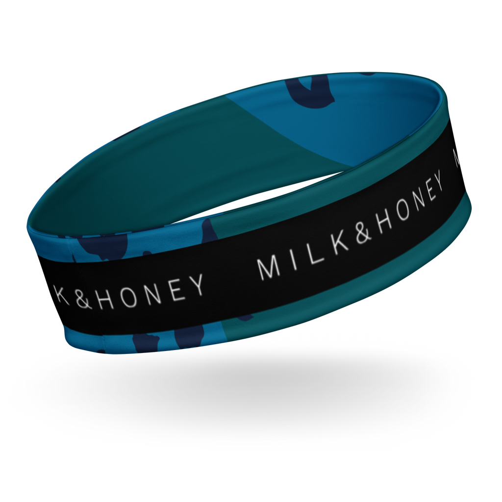 Teal and blue patterned headband with a black stripe bearing white 'MILK & HONEY' text, shown in close-up