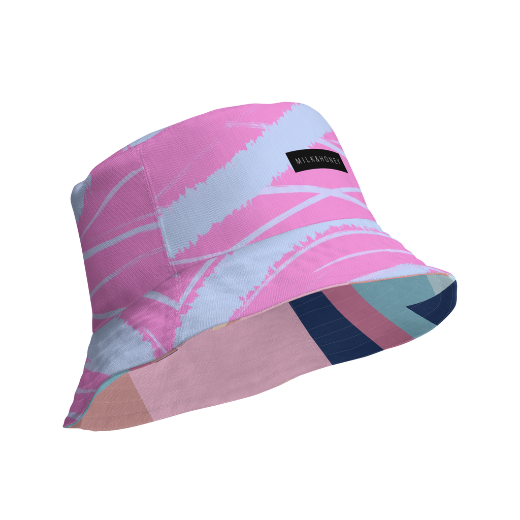 Reversible bucket hat with pink and light-blue brushstrokes, black 'MILK&HONEY' label and striped underside.