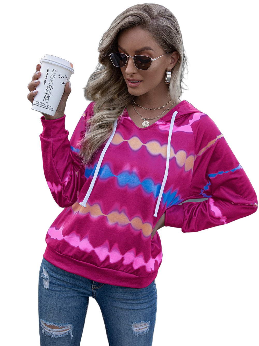 Woman wearing hot pink tie-dye hooded raglan hoodie with white drawstrings, sunglasses, holding a takeaway coffee cup.