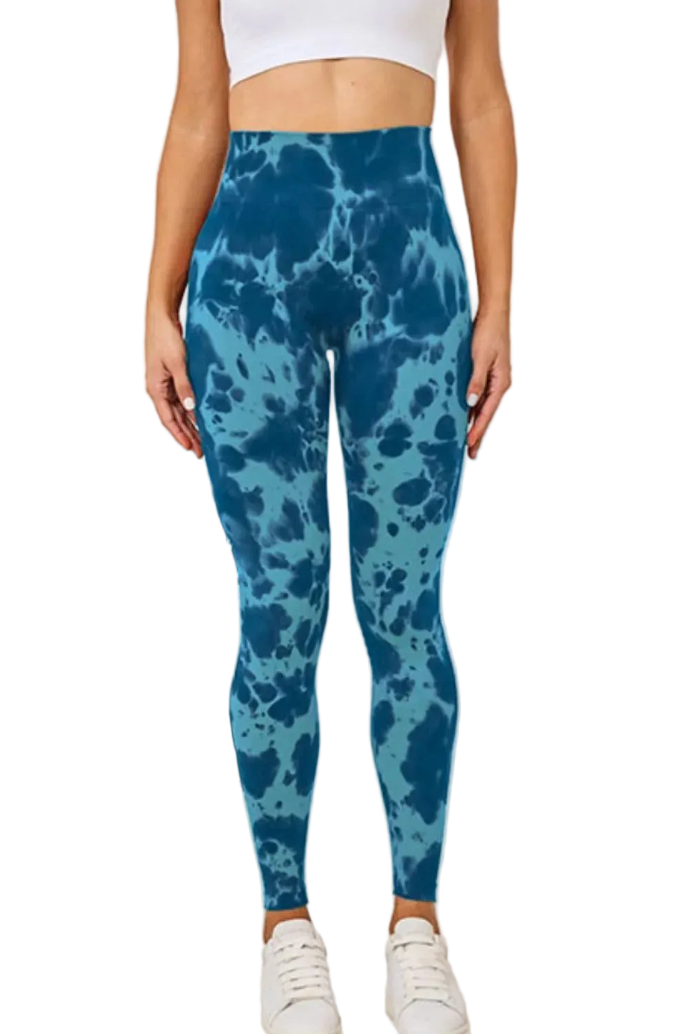 Model wearing high-waist tie-dye leggings with blue marbled pattern, cropped white top and white sneakers