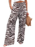 High-waist zebra-striped wide-leg pants with hand in side pocket; model holds tan clutch