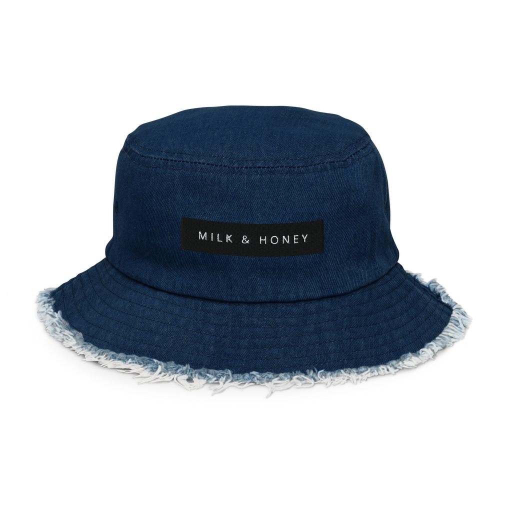 Denim bucket hat with black 'MILK & HONEY' patch, visible top stitching and frayed brim edge