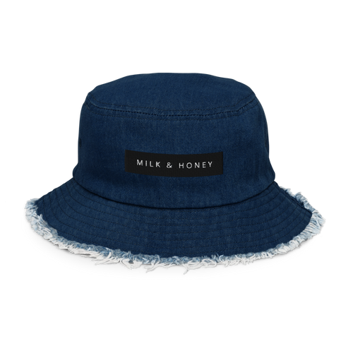 Denim bucket hat with black 'MILK & HONEY' patch, visible top stitching and frayed brim edge