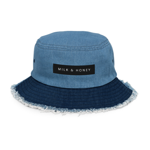 Light denim bucket hat top with stitched seams, rectangular 'MILK & HONEY' label, darker frayed brim and side eyelet