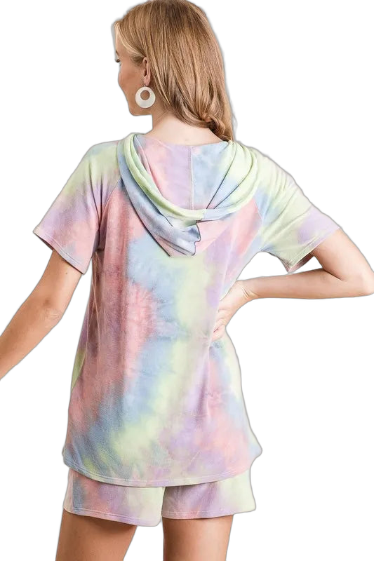 Back view of woman in pastel tie-dye hooded short-sleeve top and matching shorts, hand on hip