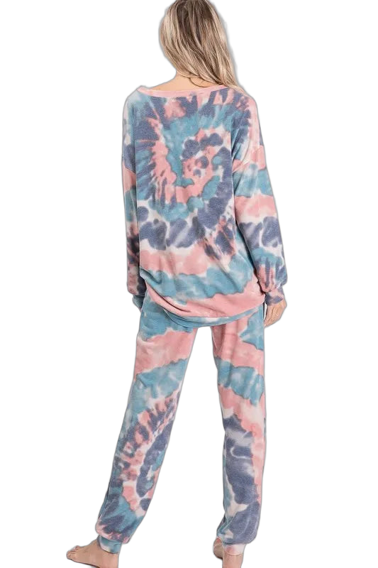 Back view of model wearing spiral pink, blue, and gray tie-dye long-sleeve top and matching jogger pants with cuffed ankles