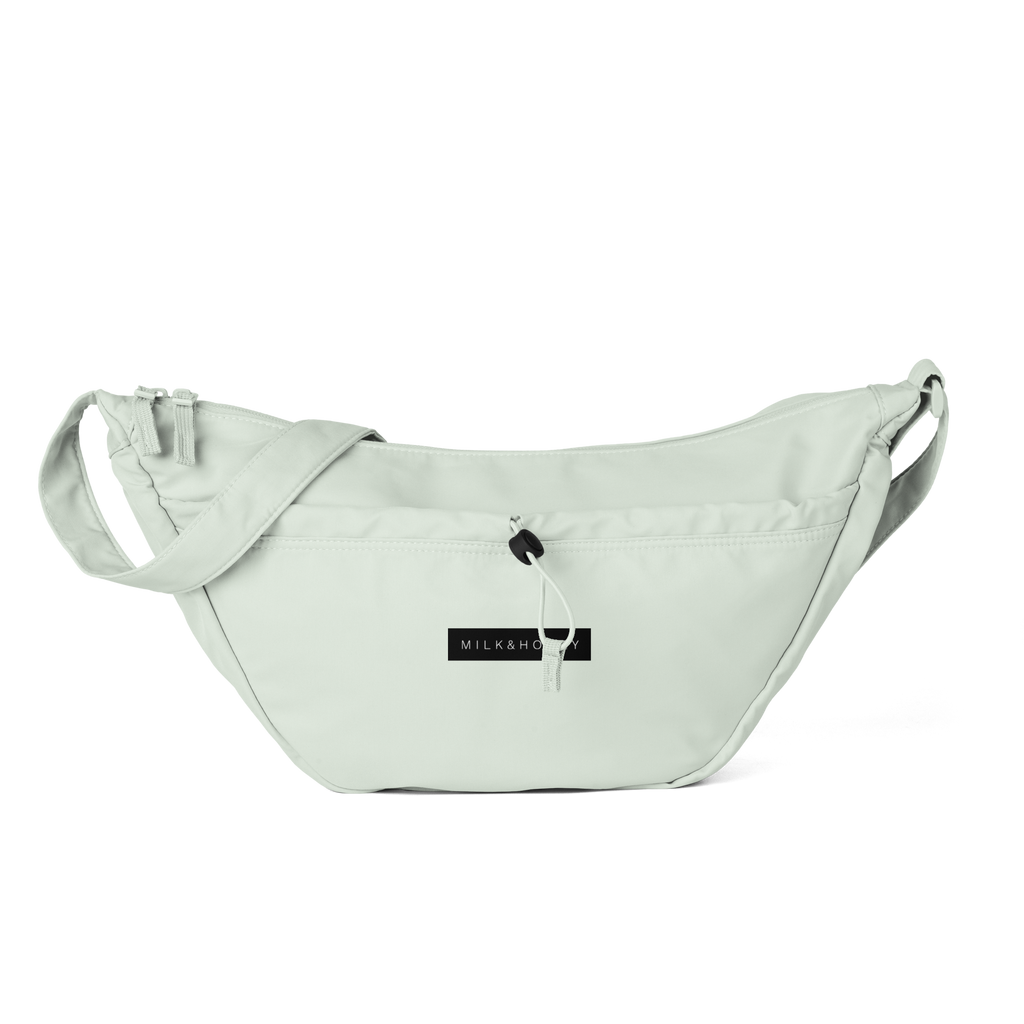 Light green padded crossbody bag top with adjustable strap, front zip pocket, corded toggle and MILK&HONEY label