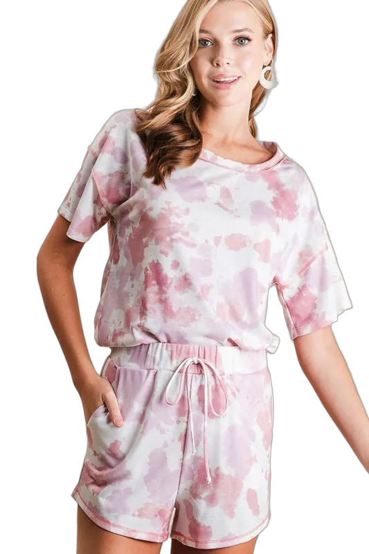 Model wearing pink and white tie-dye shorts with drawstring waist and side pockets, paired with matching short-sleeve top