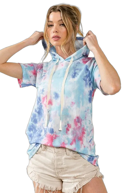 Model wearing short-sleeve pastel tie-dye terry hoodie with long white drawstrings and frayed cutoff shorts